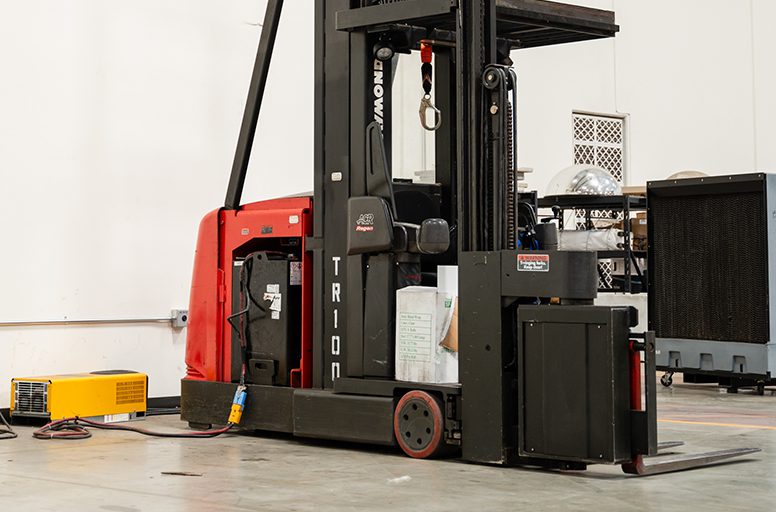 A large red and black forklift is parked in the middle of an area.