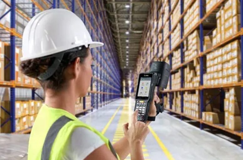 A woman in a warehouse holding a cell phone.