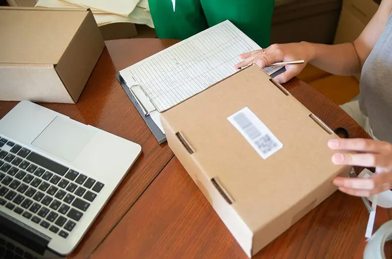 A person is writing on the box of a package.