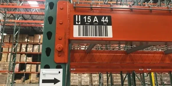 A warehouse with red and green racks and a black bar code.